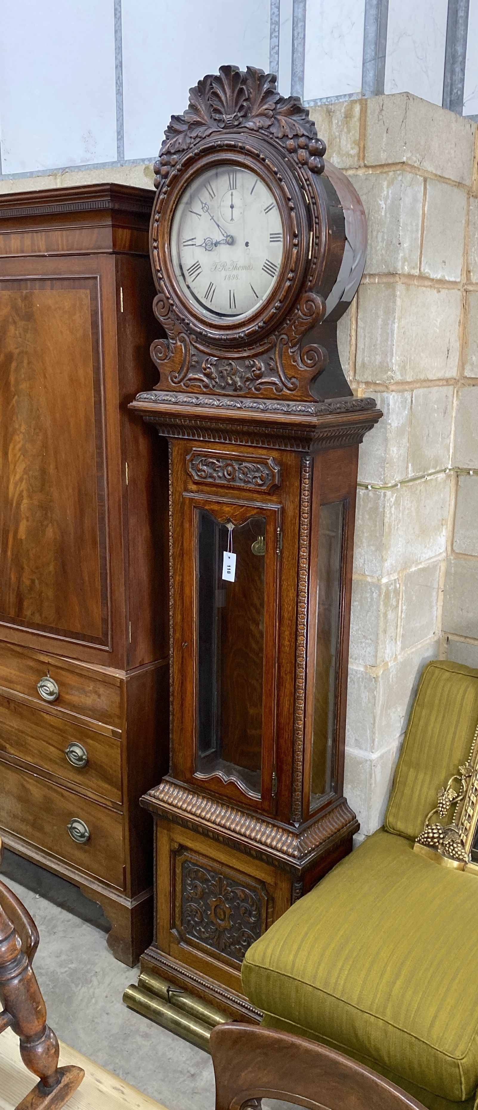 A Victorian carved oak eight day longcase clock by J.R.Thomas dated 1898, having silvered circular dial over glazed door, height 226cm
